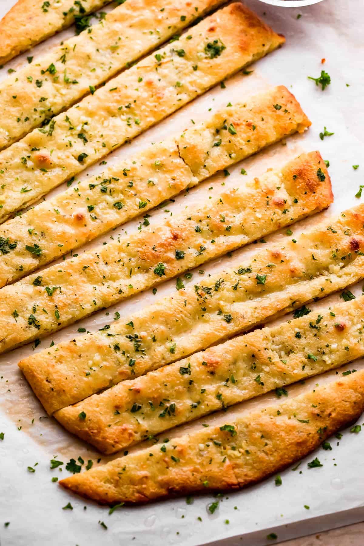 overhead shot of an oval shaped baked keto bread cut into long breadsticks, and served with marinara sauce on the side.