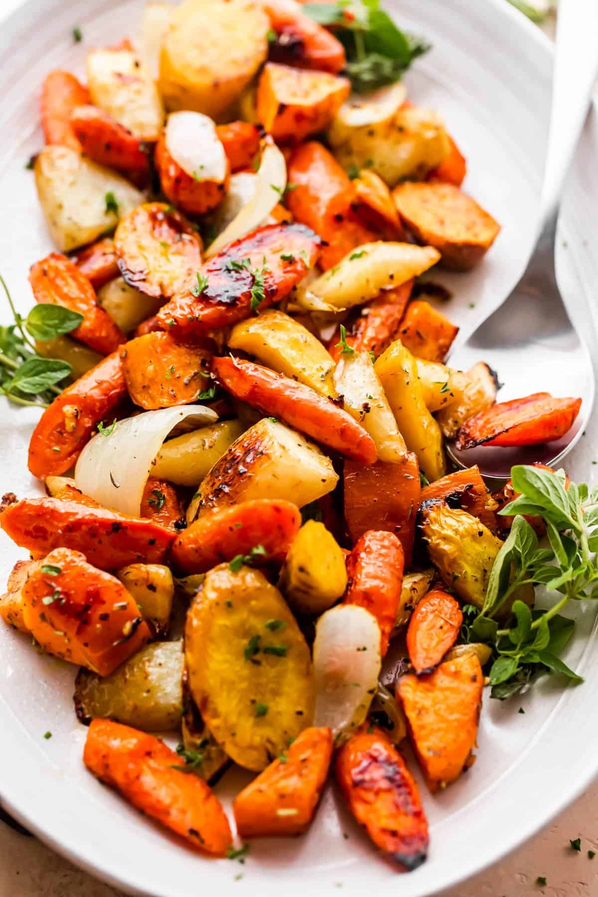 roasted chopped carrots, parsnips, sweet potatoes, and onions served on an oval plate