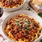 Two bowls of tagliatelle pasta topped with homemade bolognese sauce.