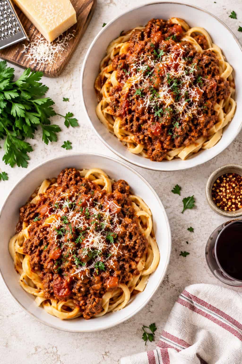 This easy Bolognese sauce recipe is made with ground beef, tomatoes, garlic, and fresh herbs, then simmered until rich and thick. Ready in about an hour! Two bowls of tagliatelle pasta topped with homemade bolognese sauce.