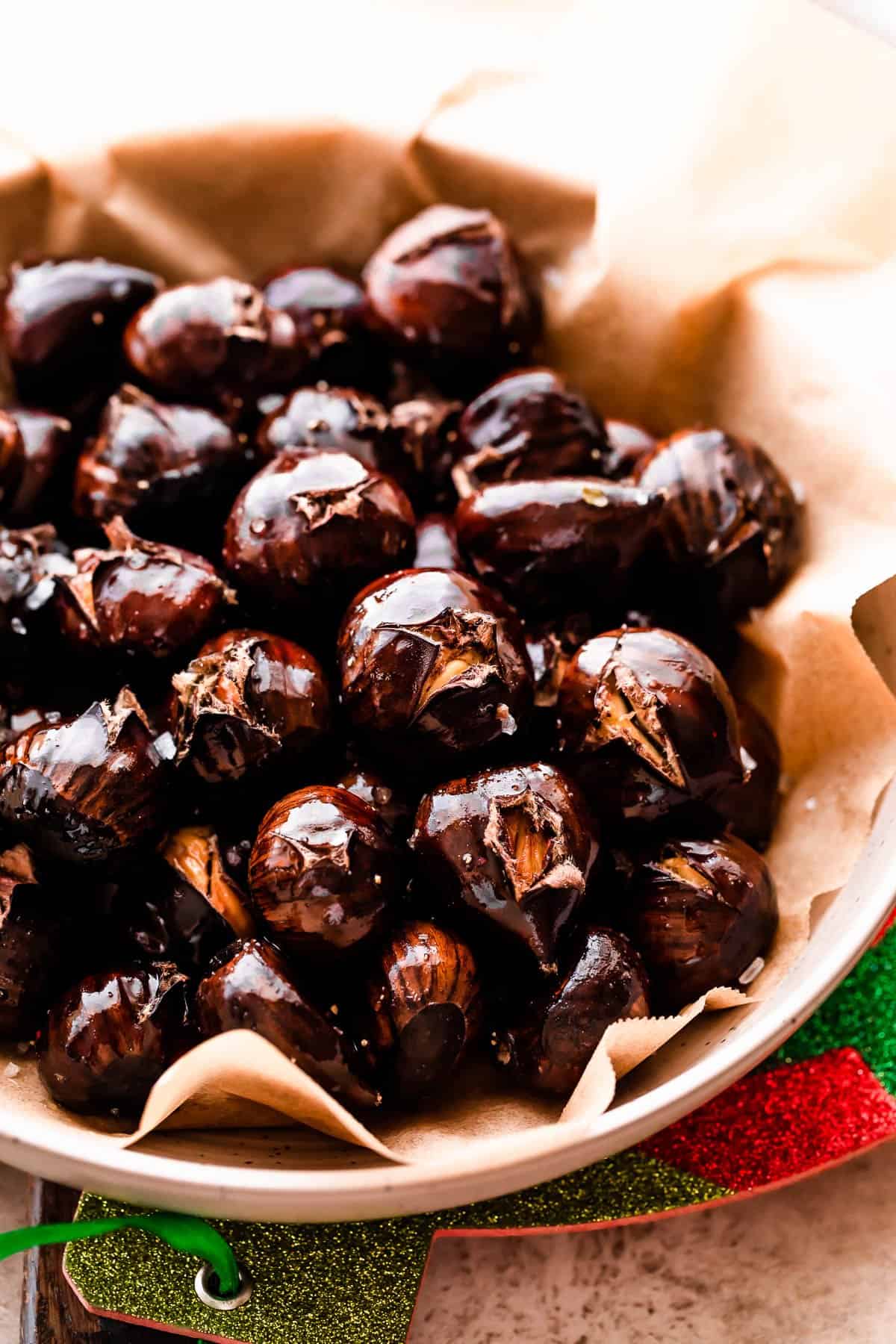 roasted chestnuts served in a bowl covered with brown parchment paper.