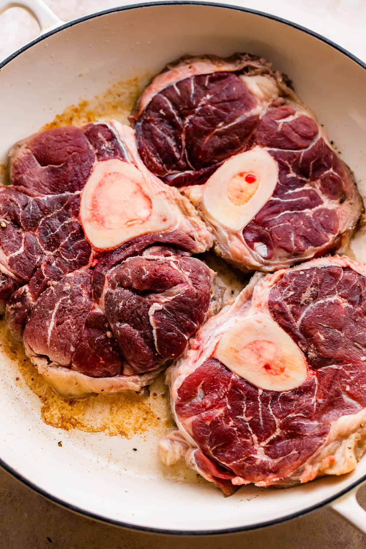 Three large bone-in beef shanks in a braiser.