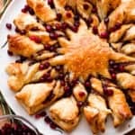 puff pastry dough shaped into a star with sixteen rays and stuffed with pesto and garnished with pomegranate arils.