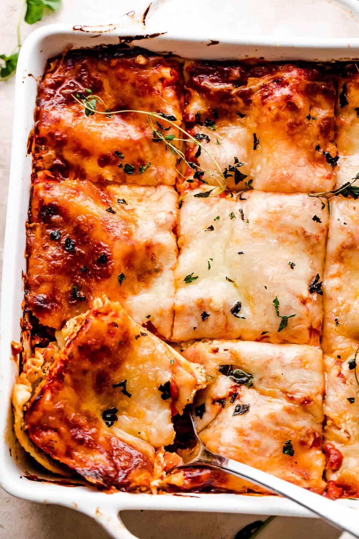 overhead shot of a square baking dish with vegetable lasagna cut in squares.