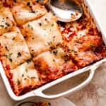 overhead shot of a square baking dish with vegetable lasagna cut in squares and a serving spoon inside the baking dish.