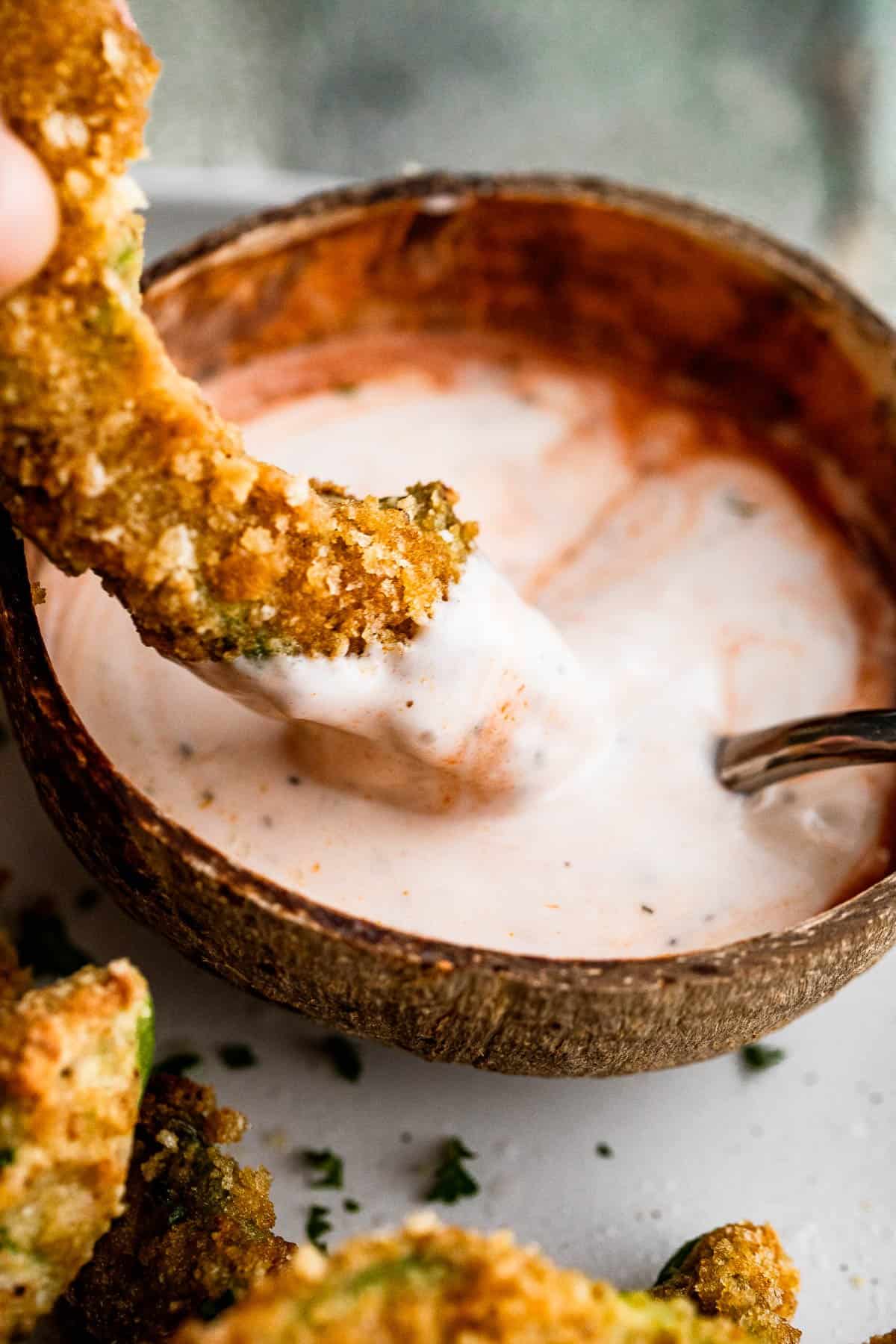 Dipping avocado fry in buffalo ranch dipping sauce.