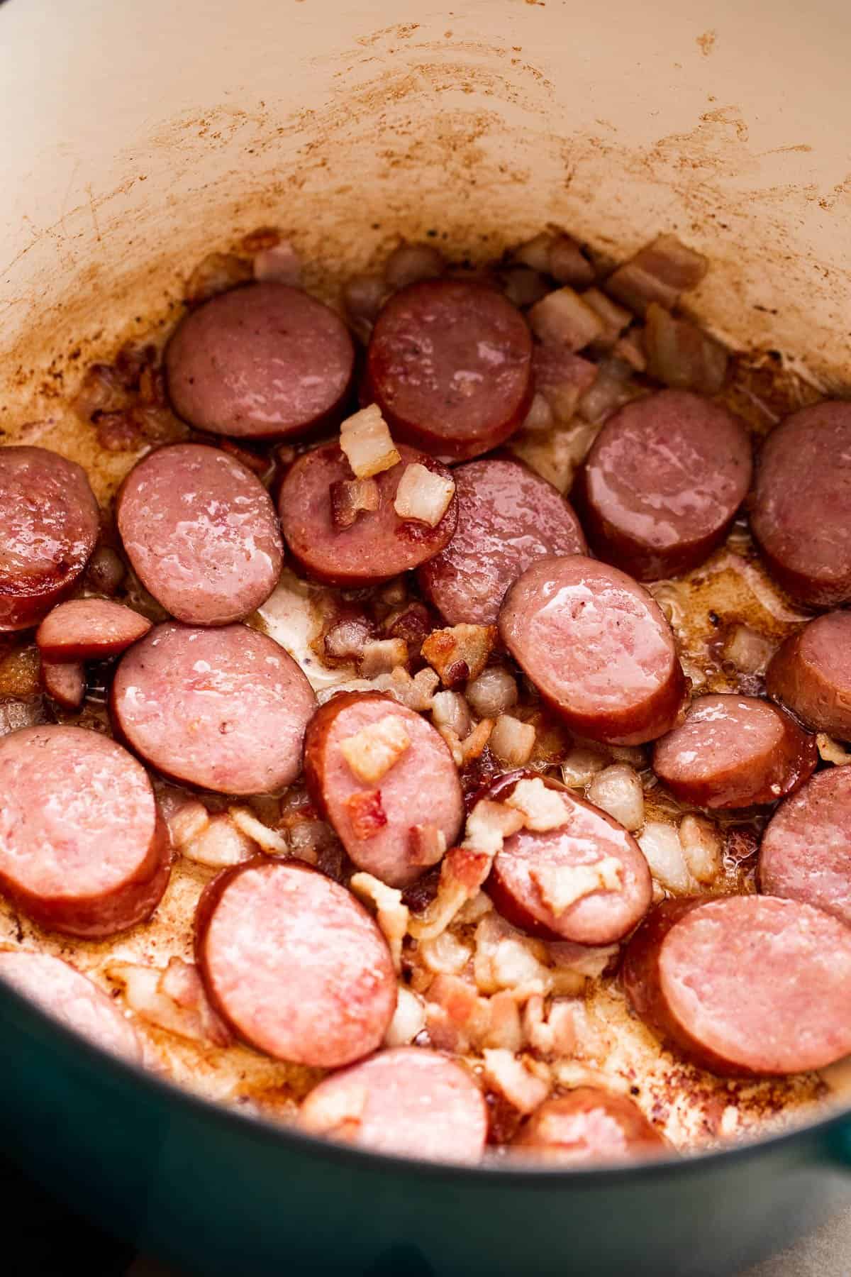 cooking sliced andouille sausage in a Dutch oven.