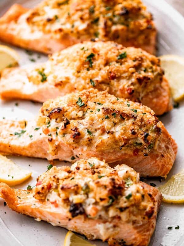 side shot of four crab stuffed salmon fillets arranged on a long oval plate.