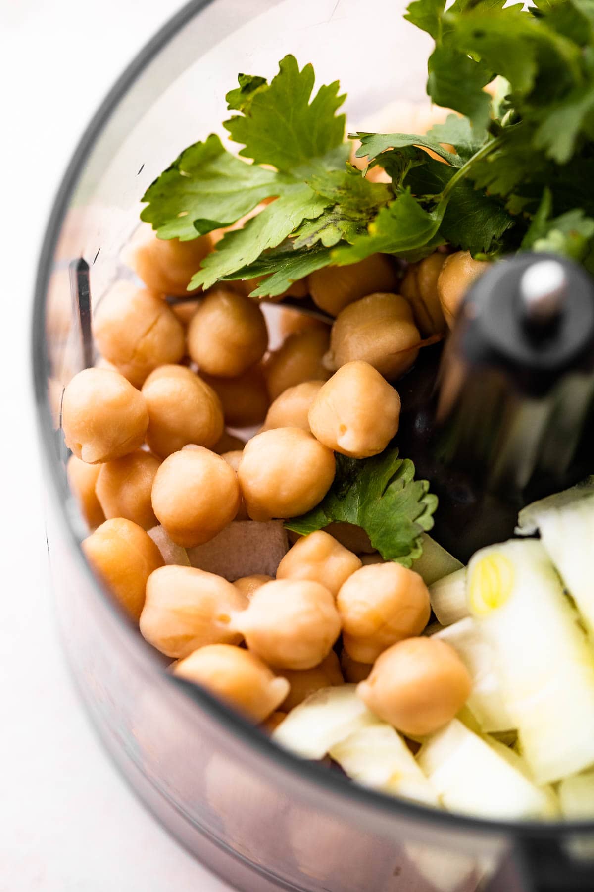 Chickpeas and cilantro leaves in a food processor.