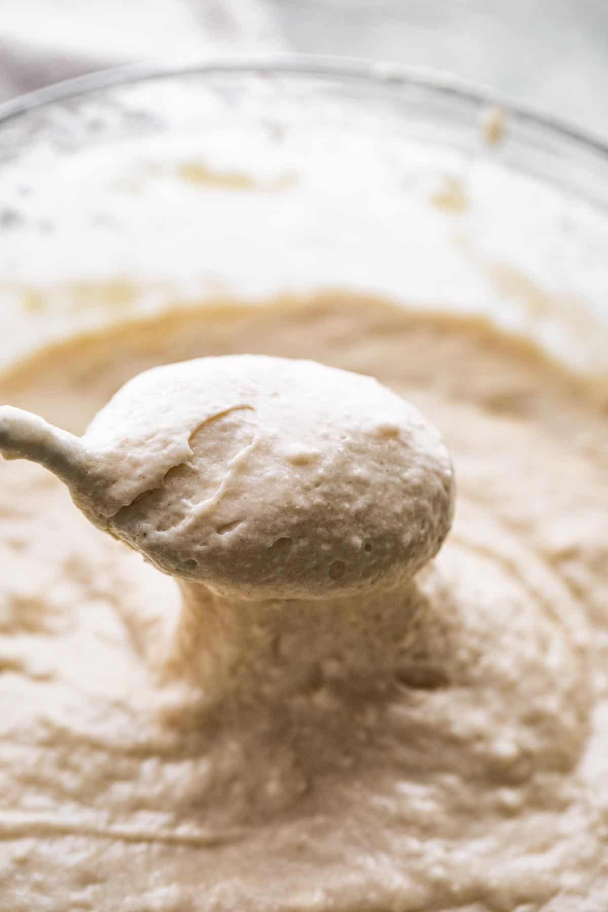 Spooning out drop scones batter from a mixing bowl.