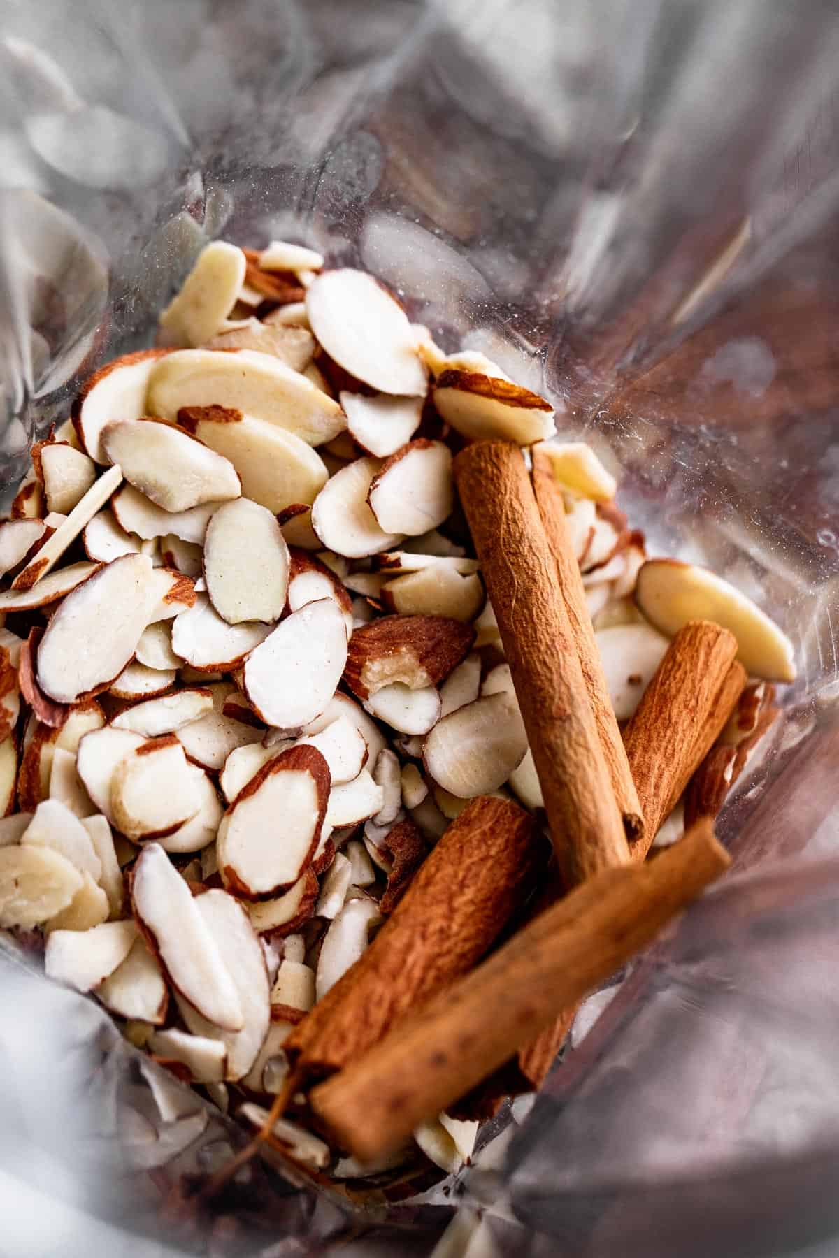 Overhead image of sliced almonds and cinnamon sticks in a blender.
