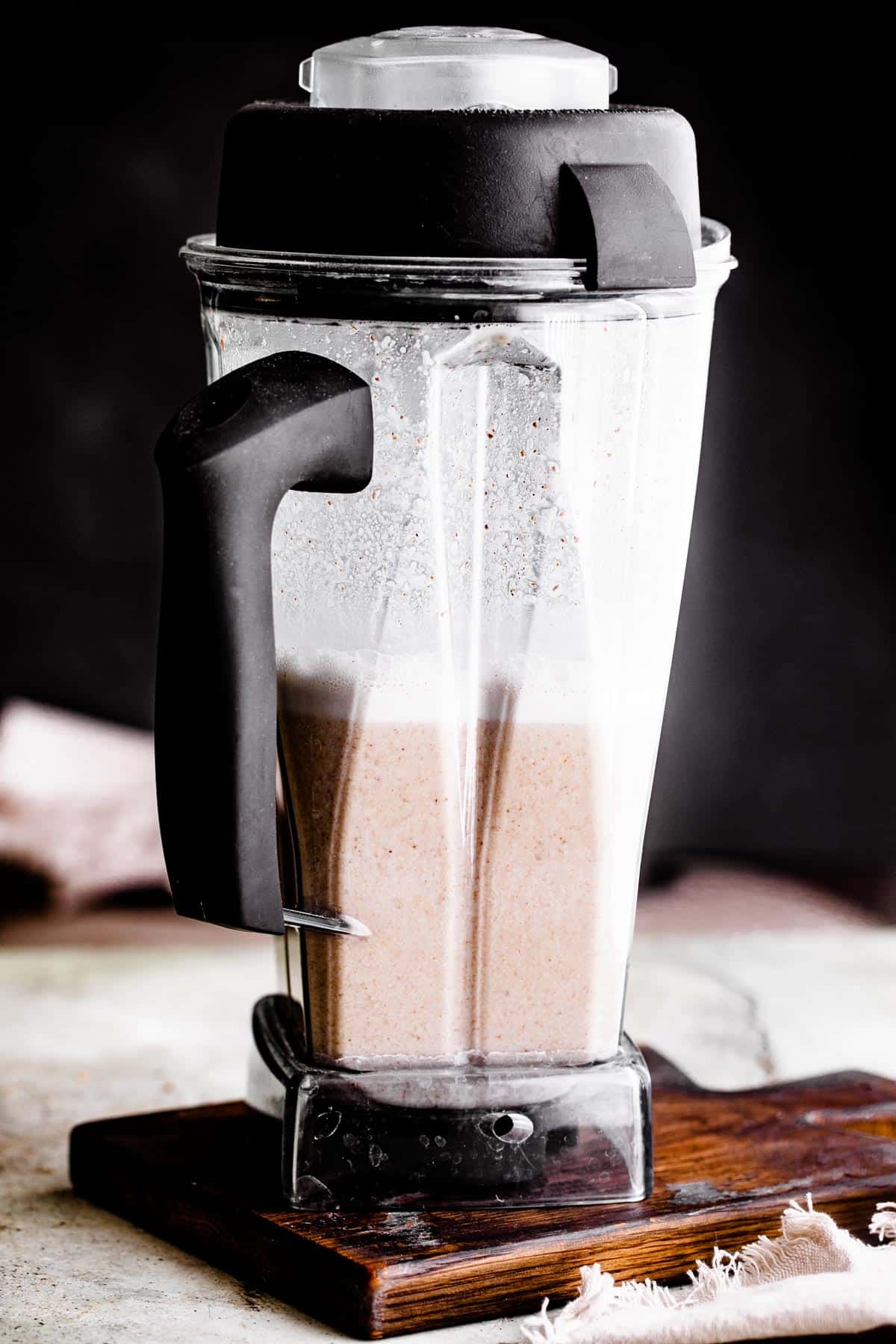 photo of a blender jug with blended rice, water, cinnamon sticks, and almonds inside of it.