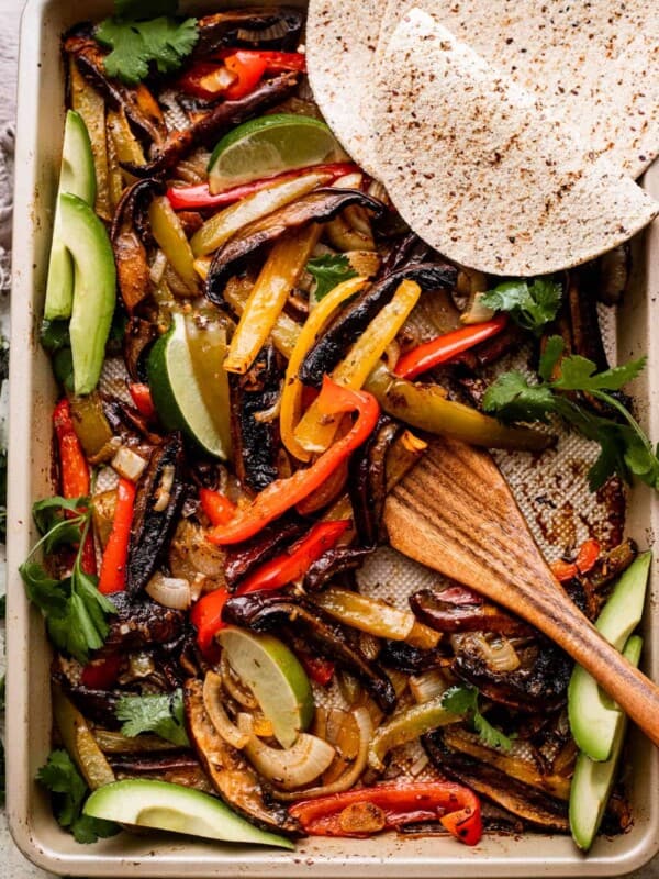 overhead shot of a baking sheet with Portobello Mushroom Fajitas and flour tortillas arranged in the top right.