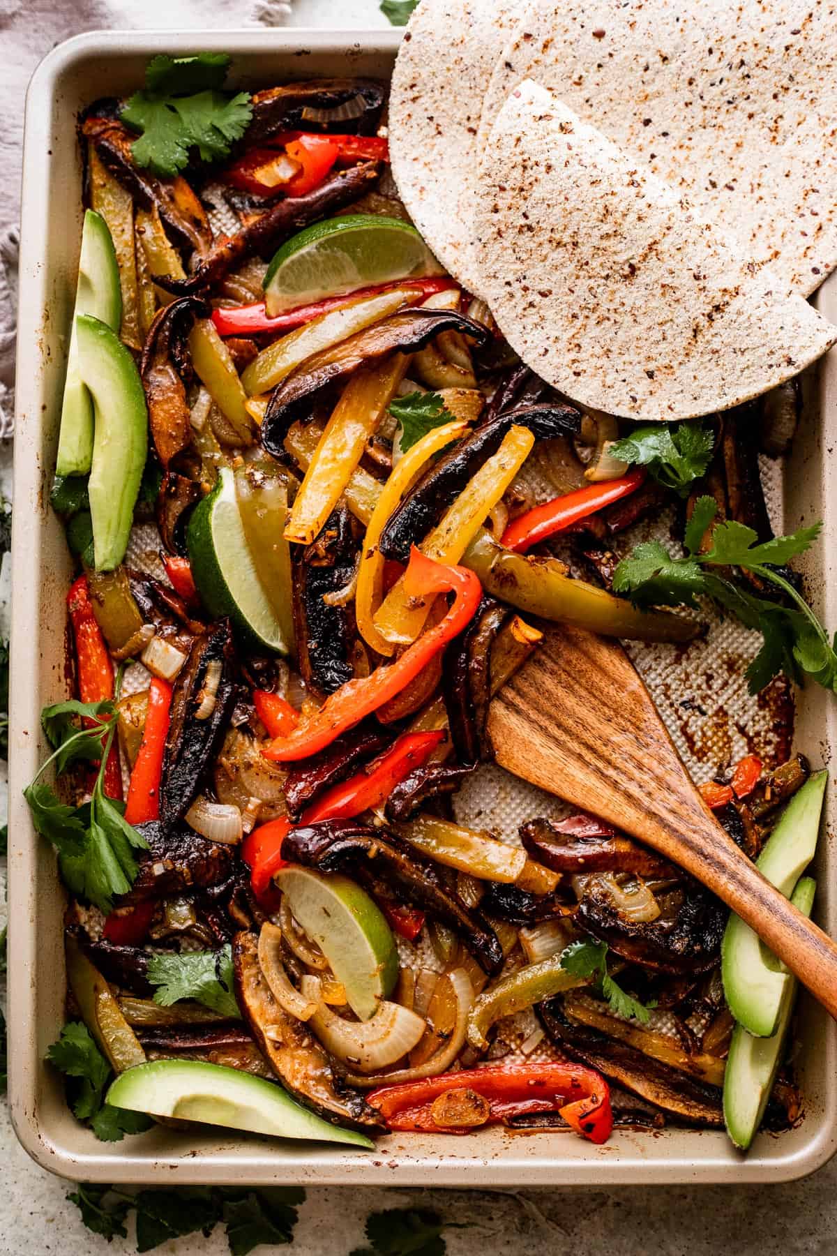 overhead shot of a baking sheet with Portobello Mushroom Fajitas and flour tortillas arranged in the top right.