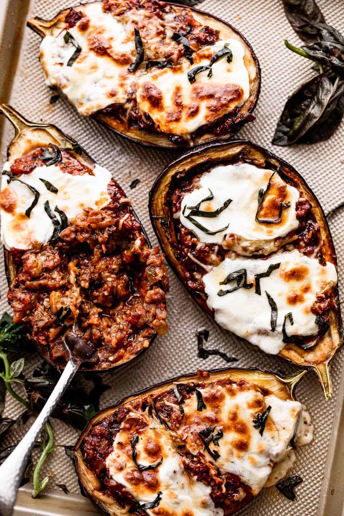 four eggplant halves stuffed with a tomato parmesan mixture, topped with melted mozzarella cheese, and arranged on a baking sheet