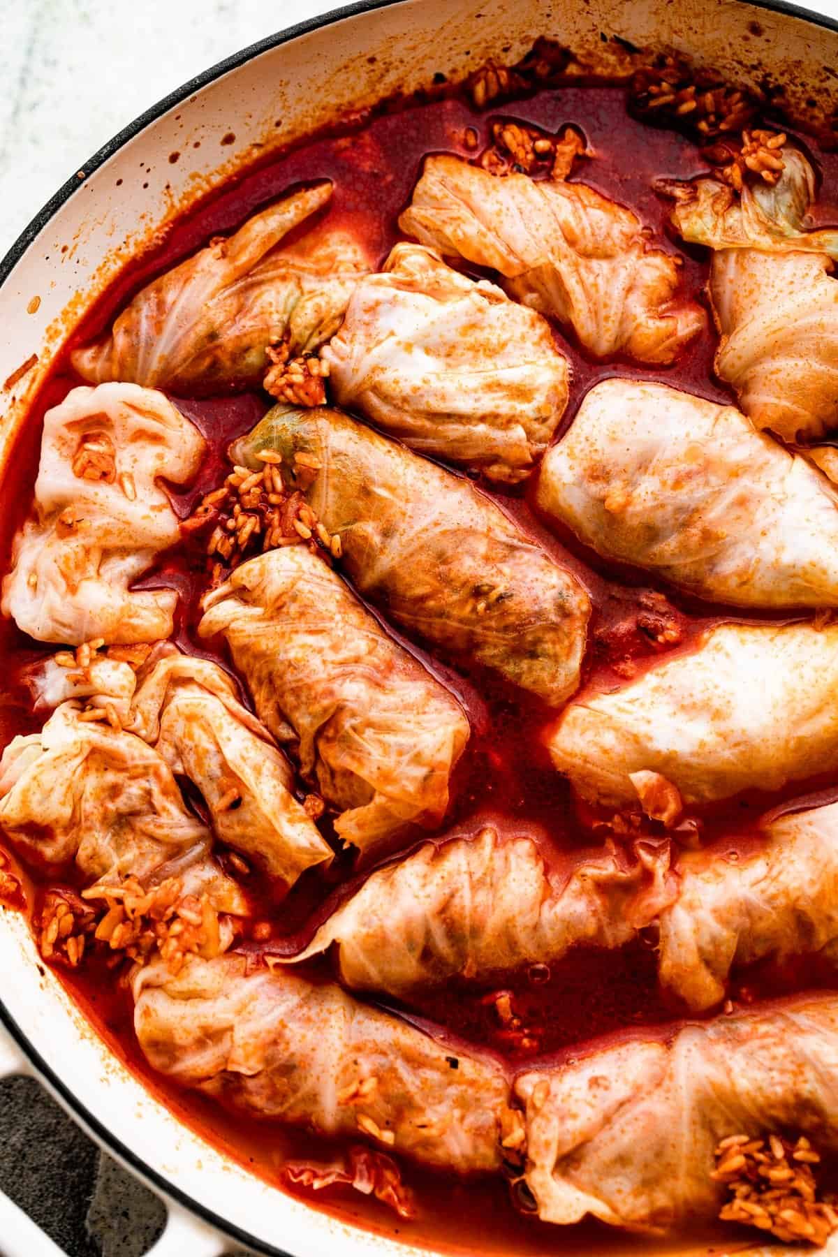 overhead shot of a white braiser with cabbage rolls in sweet paprika broth