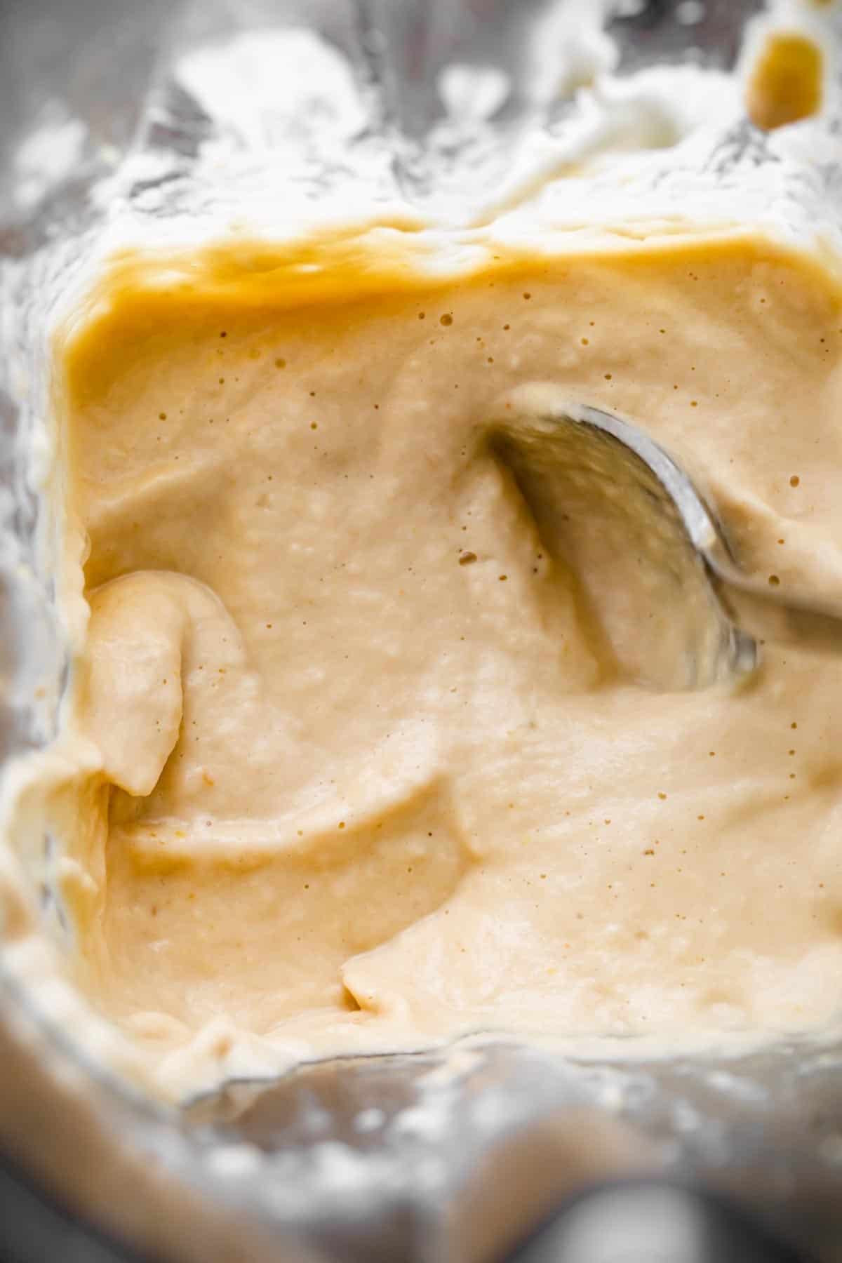 blended sauce for chicken korma with a spoon mixing through it.