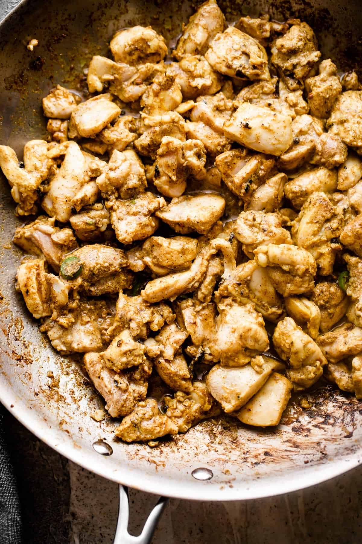 overhead shot of a cooking chicken thigh pieces in a skillet.