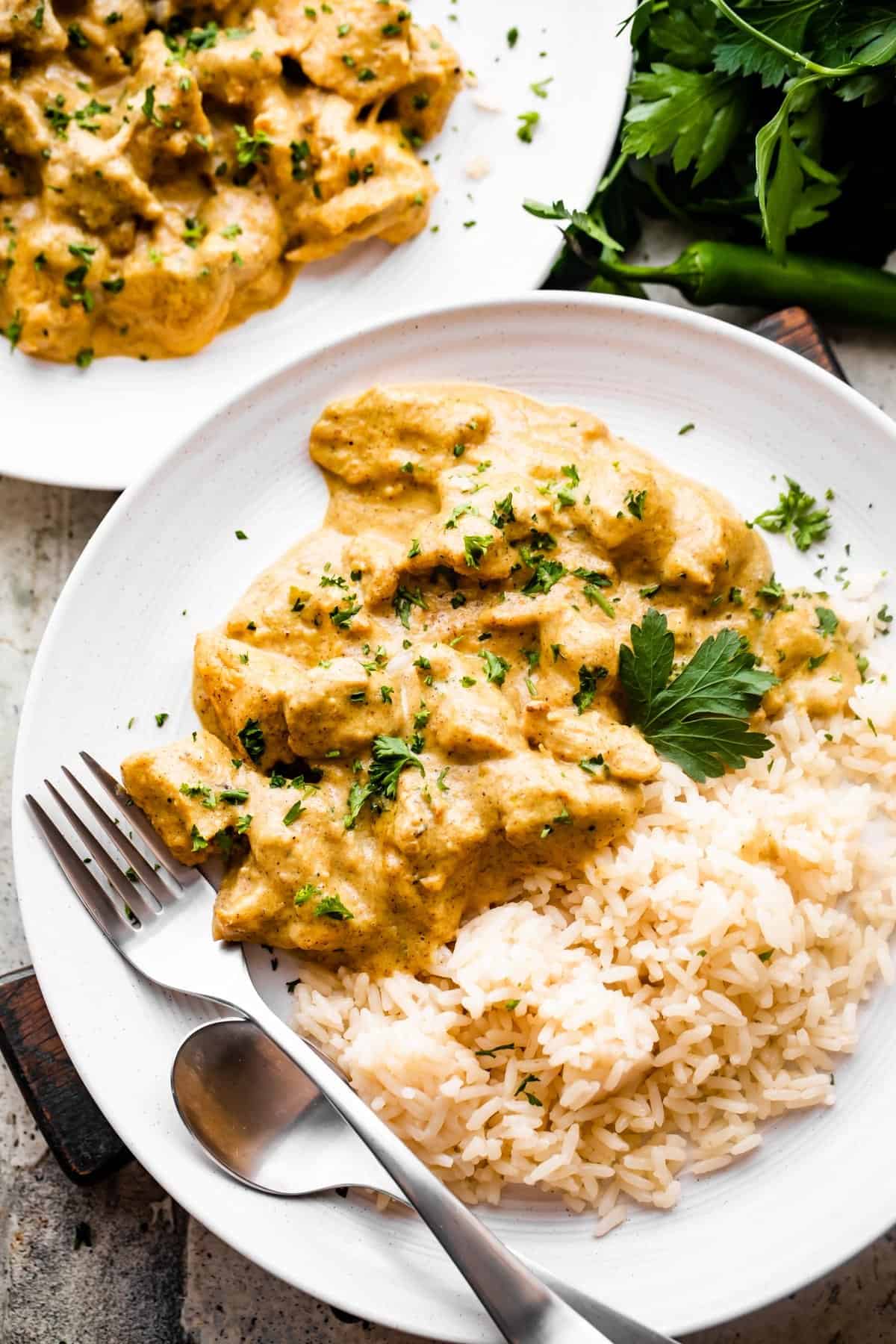 chicken korma served alongside some rice and topped with chopped cilantro.