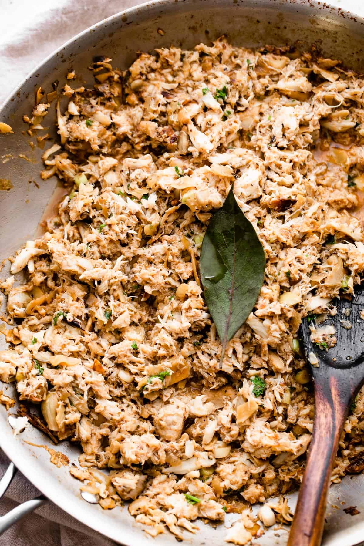 cooking crab and artichoke dip in a skillet with a bay leaf placed in the center of the dip.