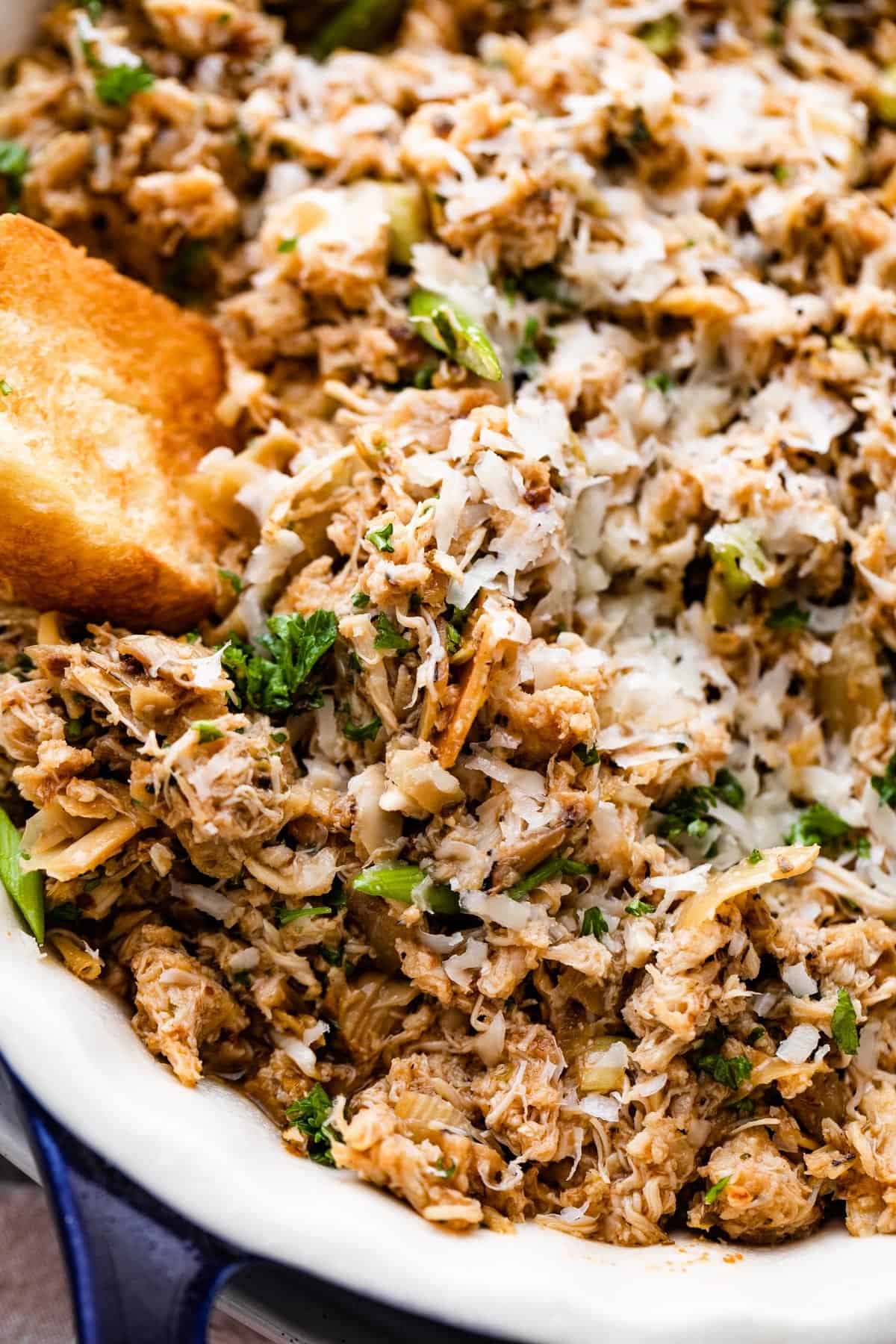 dipping into a crab artichoke dip with a toasted slice of bread