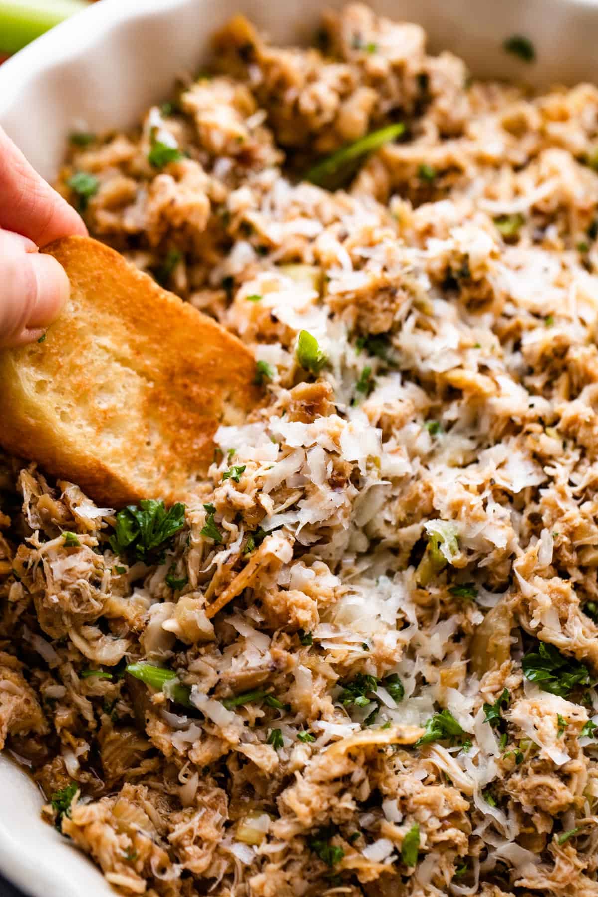 dipping into a crab artichoke dip with a toasted slice of bread