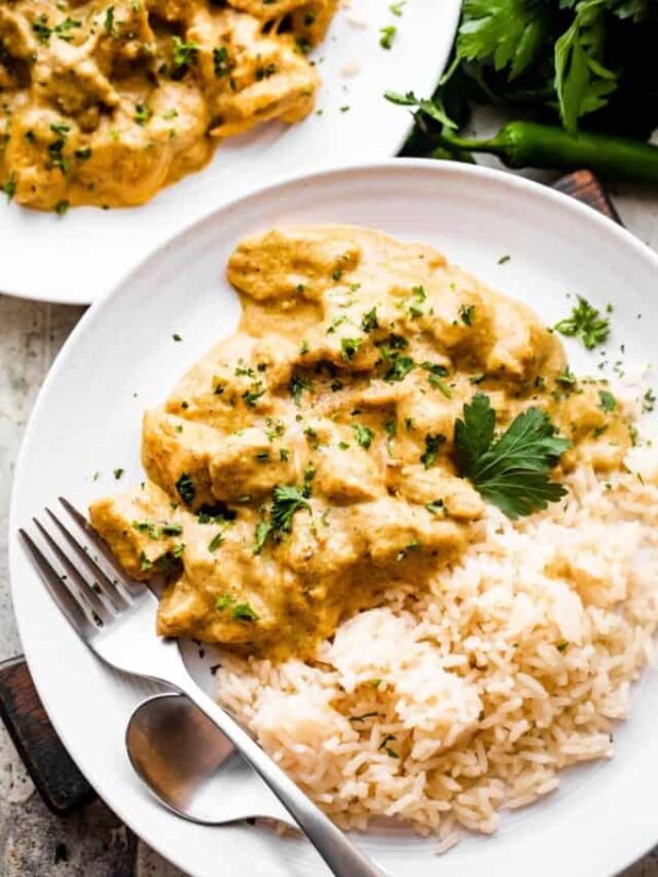 chicken korma served alongside some rice and topped with chopped cilantro.