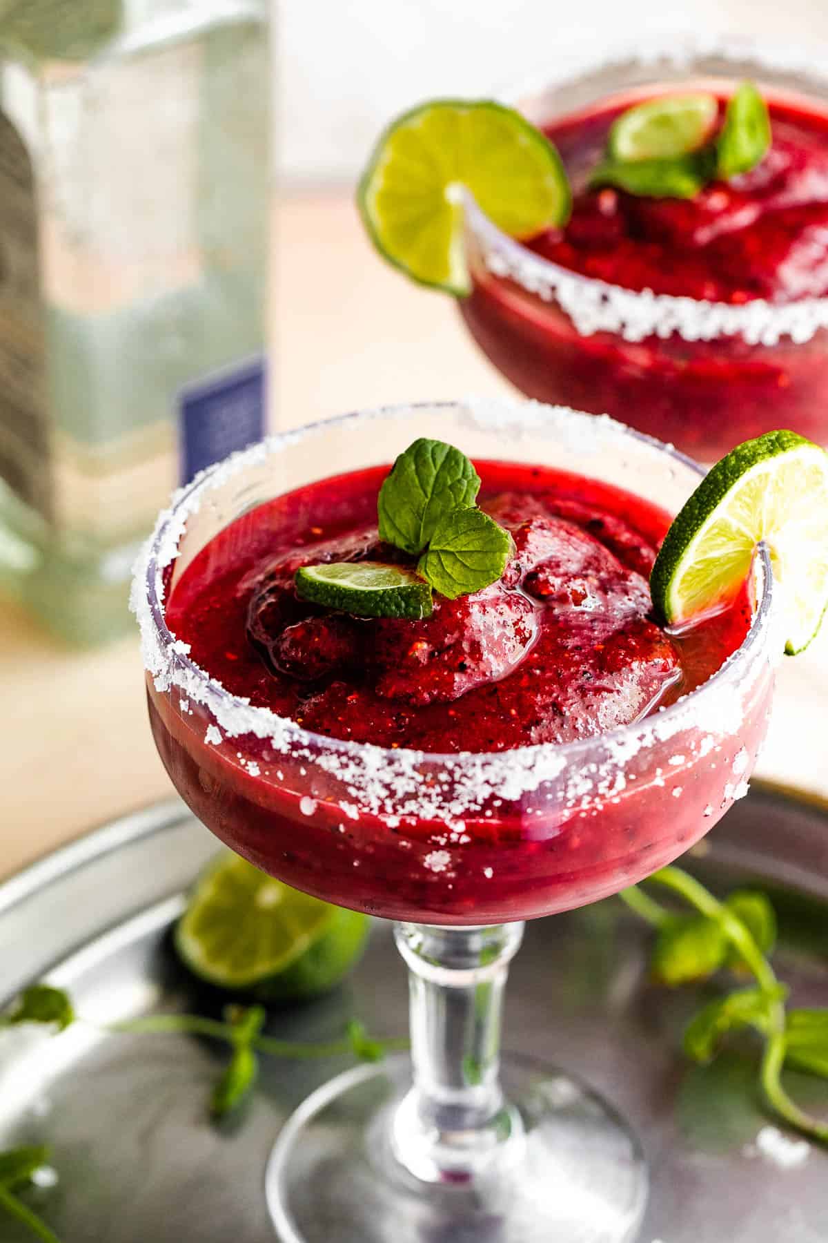 Frozen berry margaritas served in two margarita glasses.