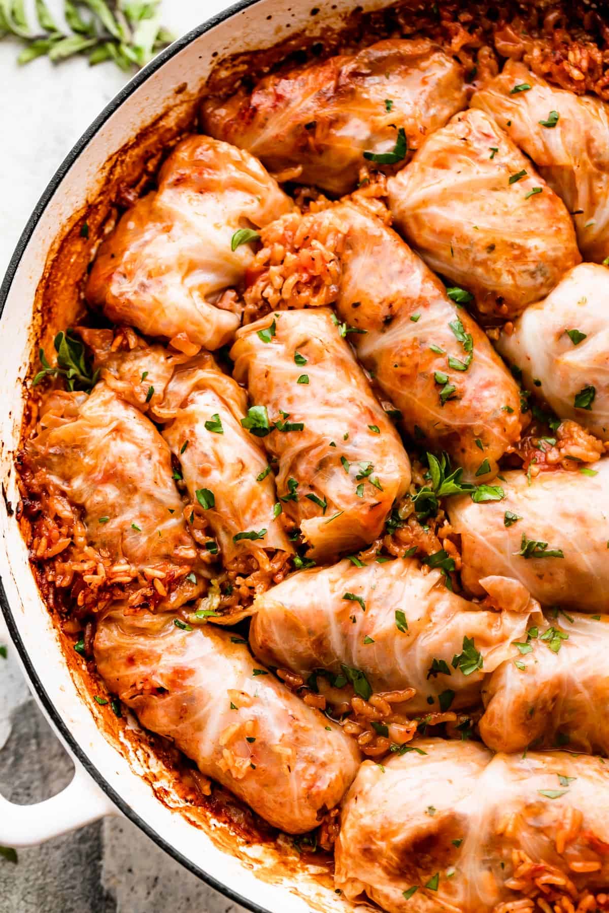 rice filled cabbage rolls arranged in a white braiser.