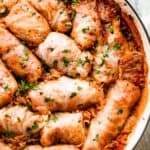 rice filled cabbage rolls arranged in a white braiser.