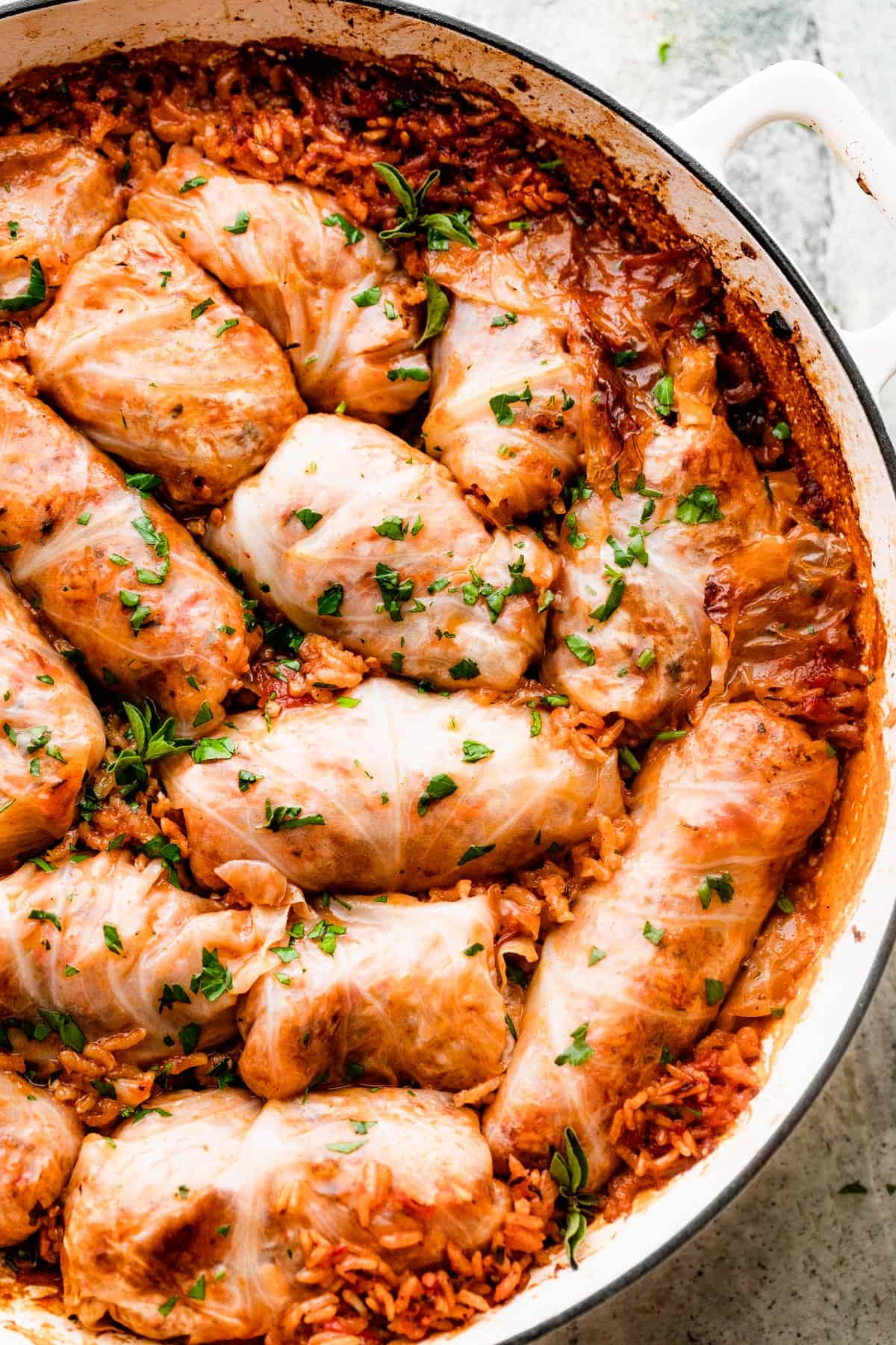 rice filled cabbage rolls arranged in a white braiser.