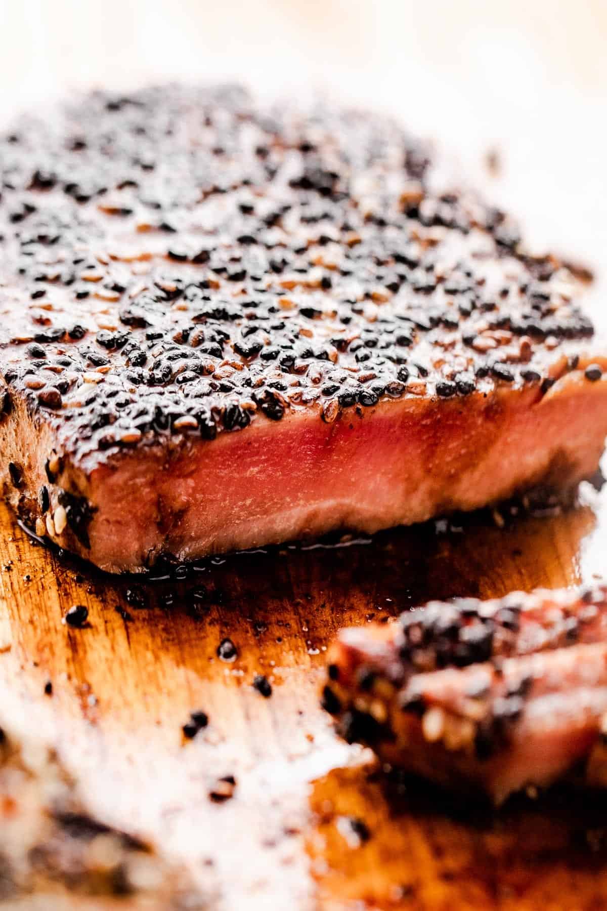 side shot of freshly cooked Sesame Crusted Tuna Steak set on a cutting board and cut through.