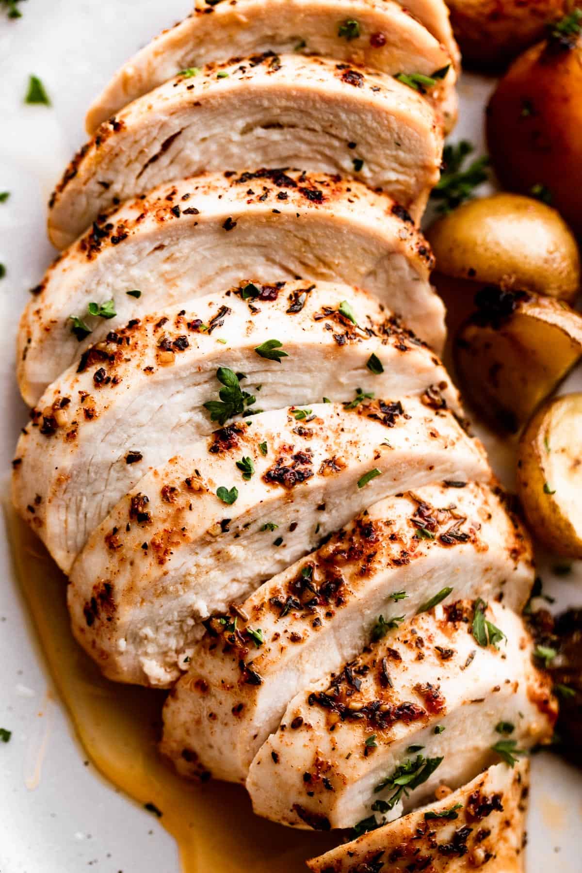 close up photo of slow cooker chicken breast, sliced and arranged on a white dinner plate.