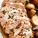 close up photo of slow cooker chicken breast, sliced and arranged on a white dinner plate.