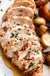 close up photo of slow cooker chicken breast, sliced and arranged on a white dinner plate.