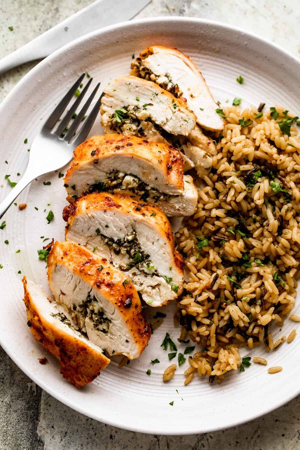 an overhead shot of a dinner plate with air fryer stuffed chicken breast cut into slices and served next to rice.