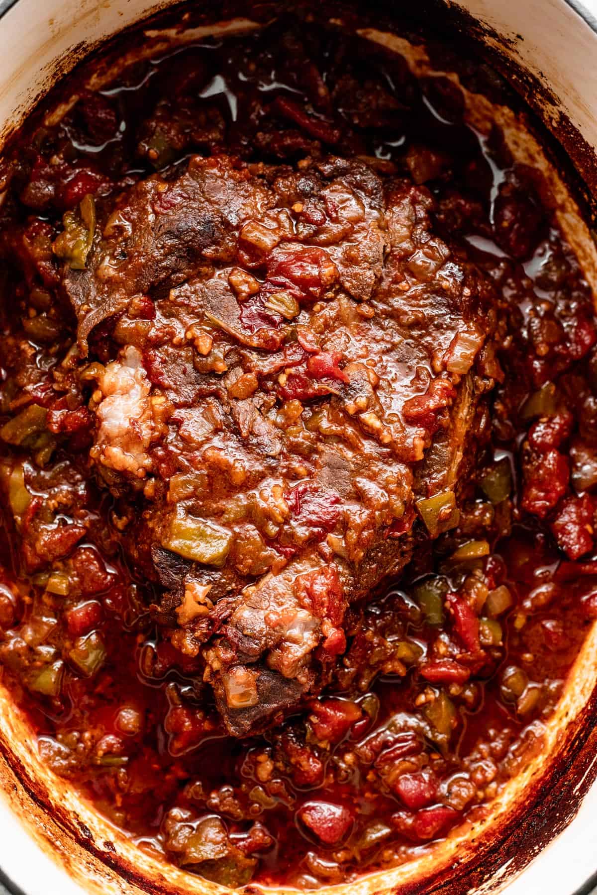 beef machaca chuck roast in a slow cooker insert topped with sauce.