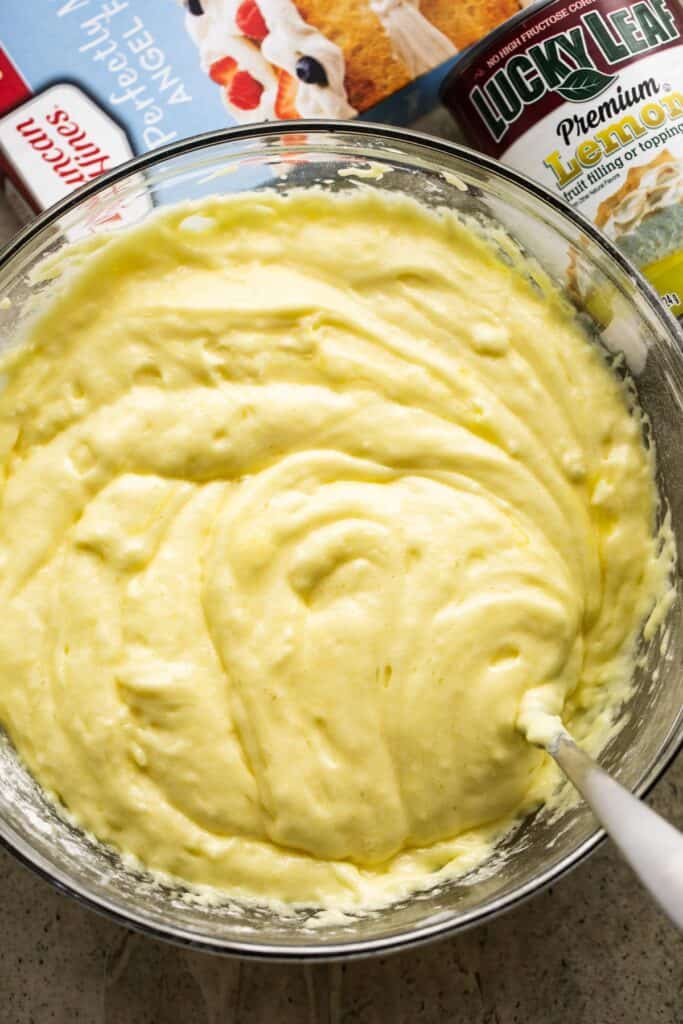 overhead shot of lemon cake batter in a mixing bowl with a spoon inside the batter.