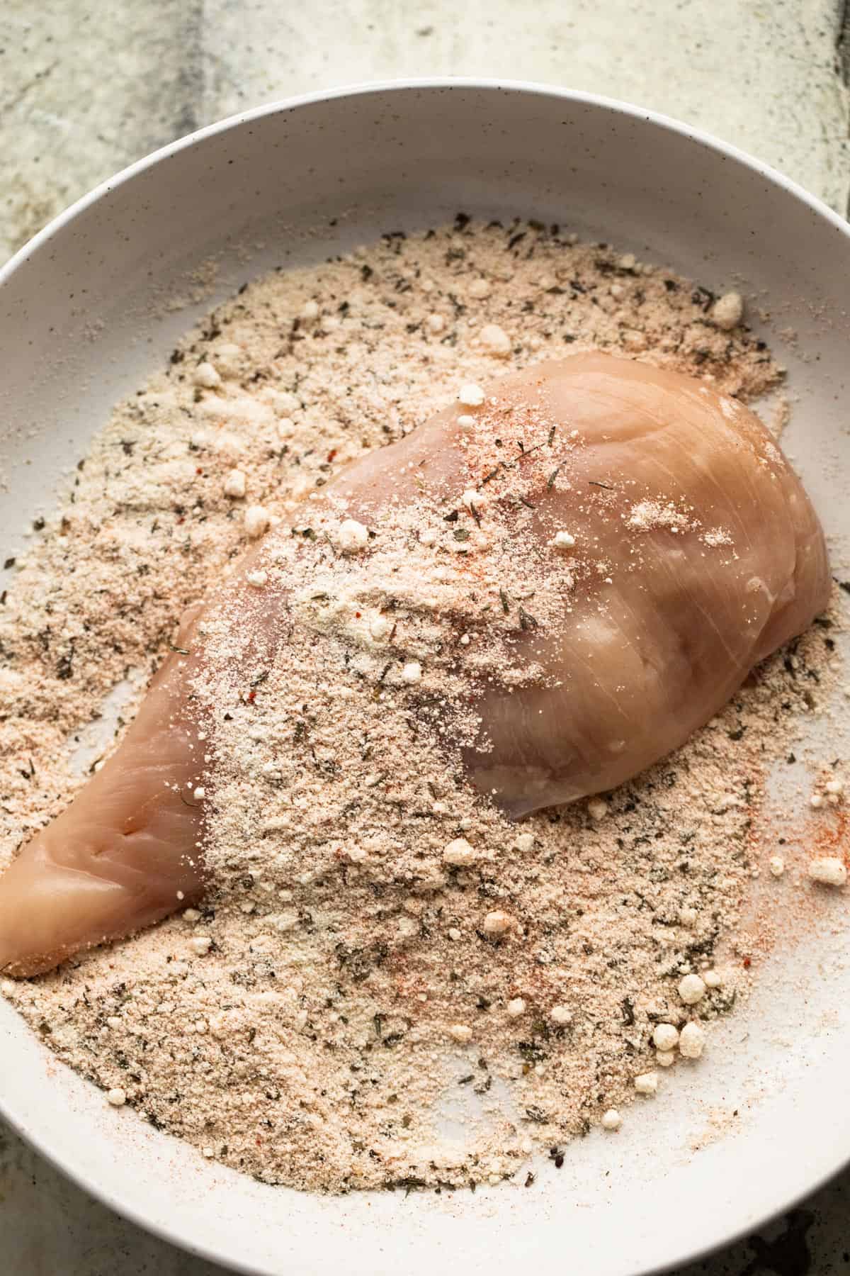 boneless chicken breast set on a plate with panko crumbs.