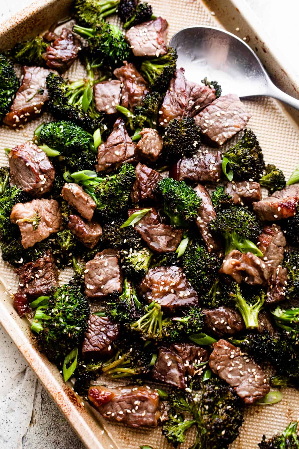 overhead shot of roasted sesame beef and broccoli arranged on a baking sheet.