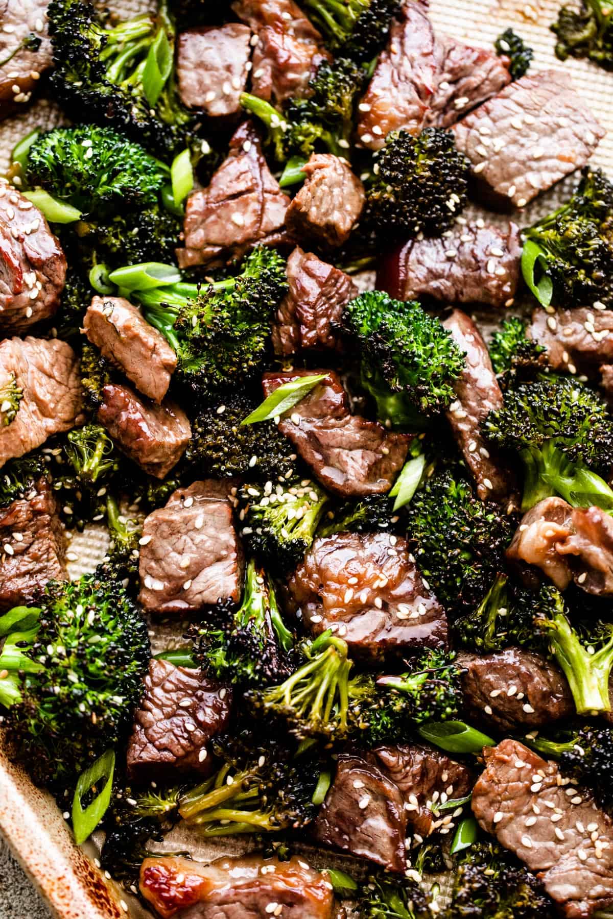 close up shot of roasted sesame beef and broccoli arranged on a baking sheet.