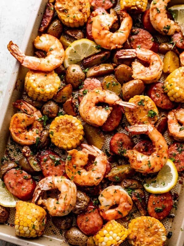 shrimp, potatoes, sausages, and corn arranged on a sheet pan and garnished with a few lemon slices.