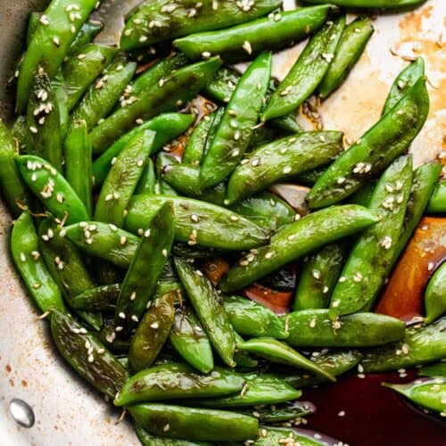 cooked sugar snap peas arranged in a silver colored skillet