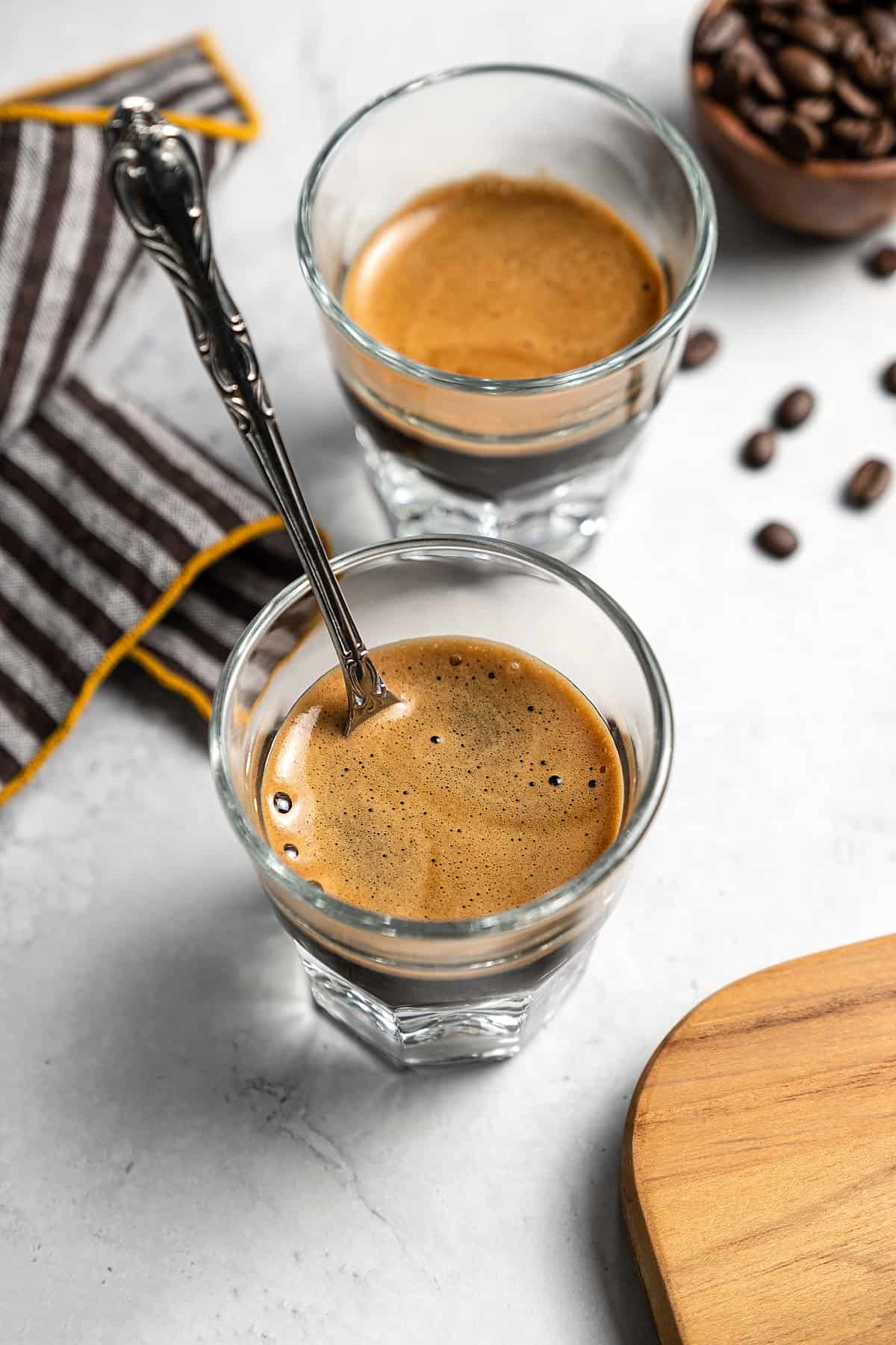 Mixing cortado coffee in two glasses