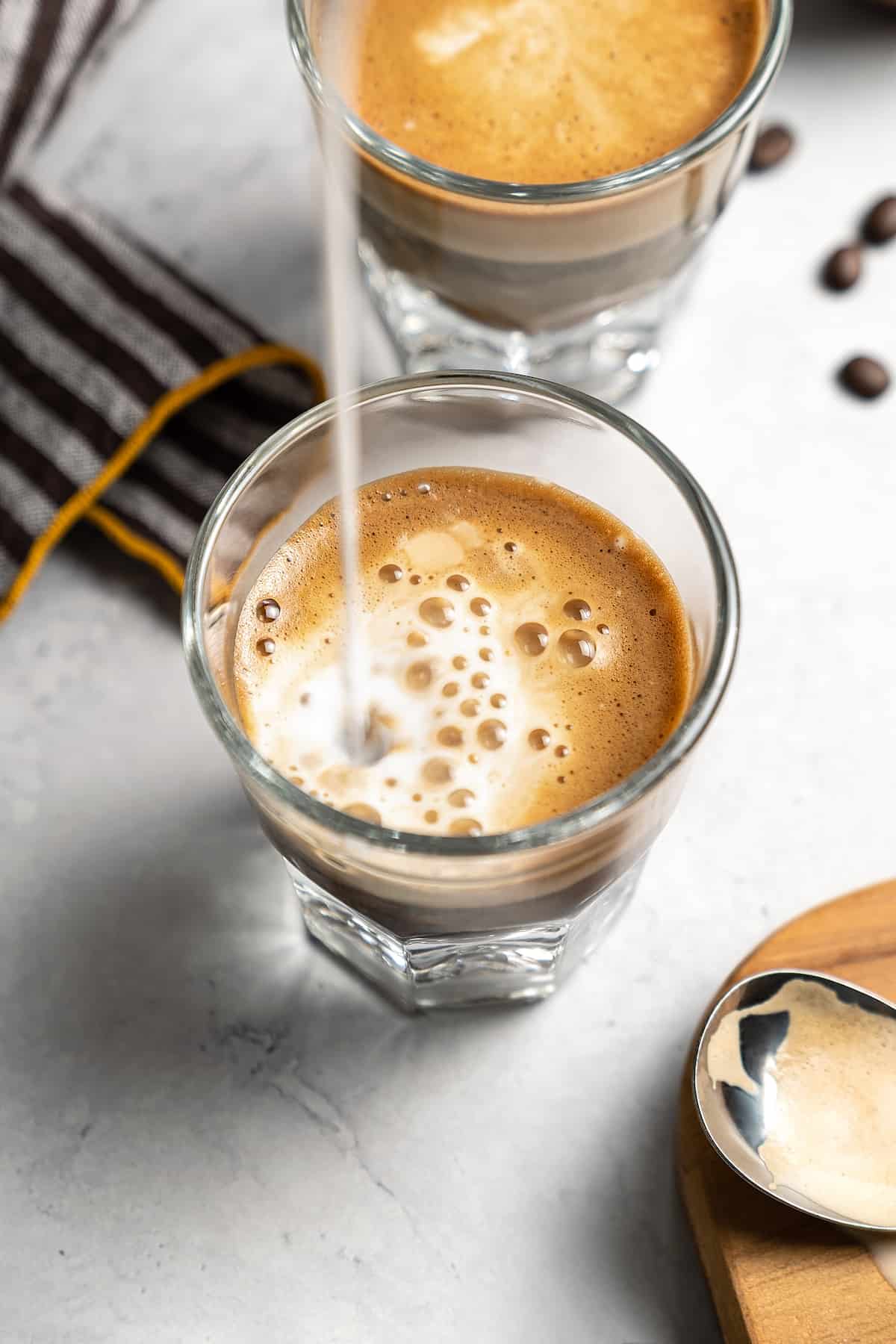 Pouring milk into a glass with coffee