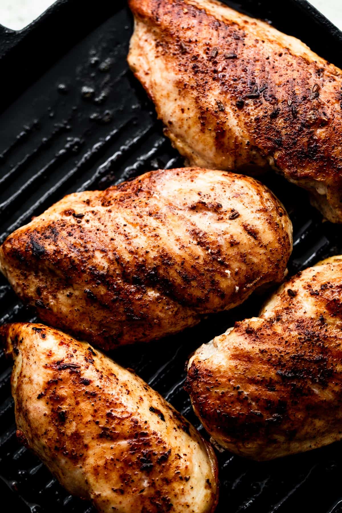 grilling four chicken breasts on a grill pan.