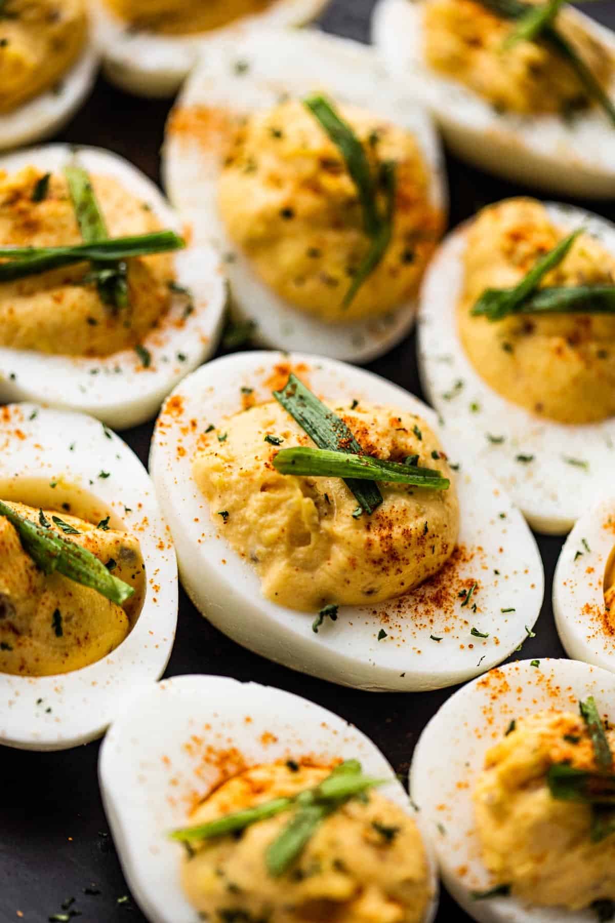 A side shot of halved eggs arranged on a black serving platter.