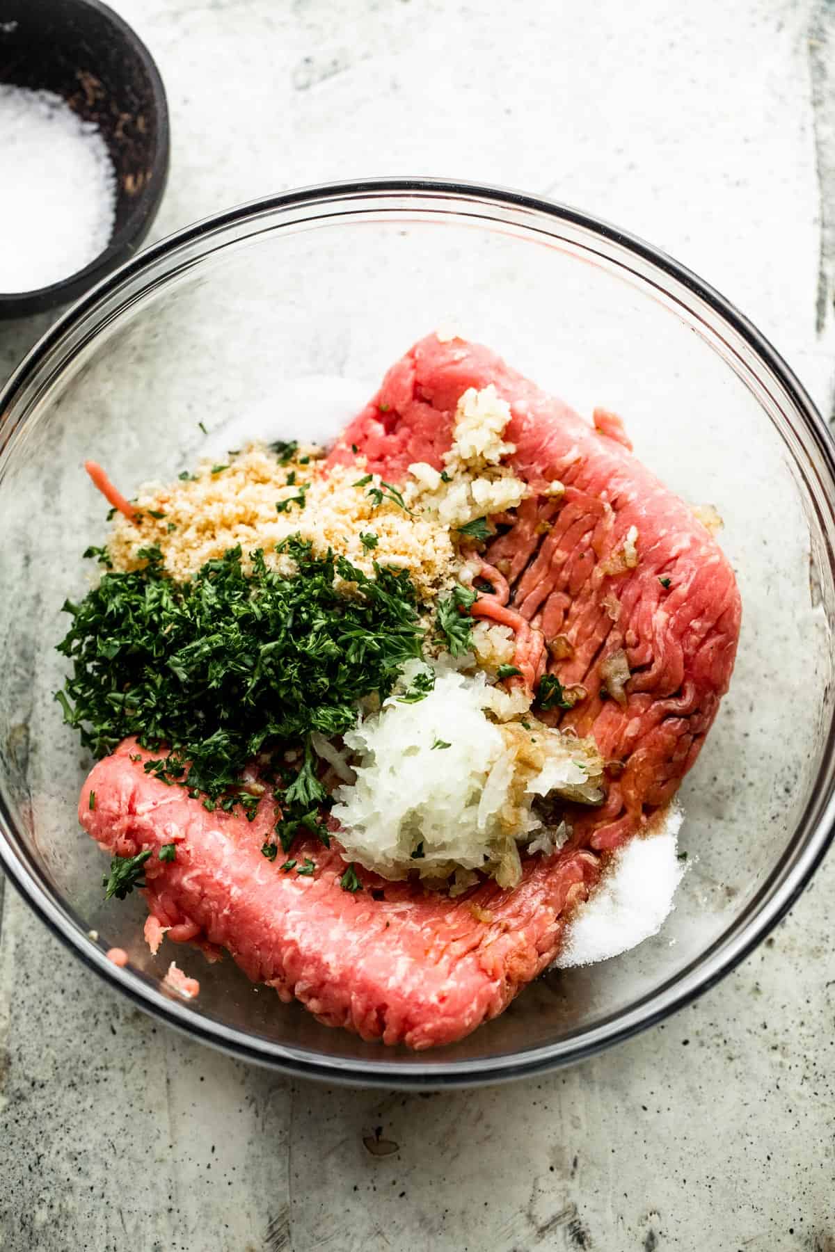 With just a few simple ingredients, these Juicy Grilled Turkey Burgers are guaranteed to turn out savory, tender, and perfect, every time! a glass mixing bowl with ingredients for turkey burgers; ground turkey, chopped herbs, seasonings, onions, mustard, and worcestershire sauce
