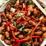 overhead shot of salt and pepper chicken in a white bowl with two chopsticks resting on top of the bowl.