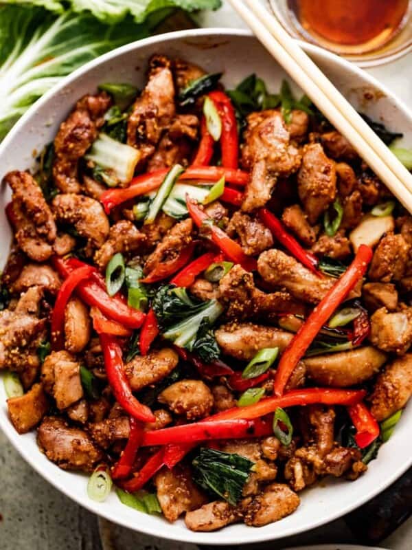 overhead shot of salt and pepper chicken in a white bowl with two chopsticks resting on top of the bowl.